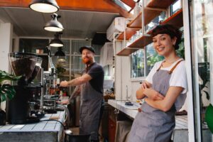 girl and guy working as baristas during their summer break from college smiling