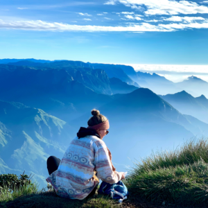 Young adult reflecting on their future while looking out over a scenic landscape during a travel experience.